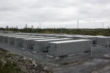 Storskaligt batterilager med rader av containrar intill en vindpark