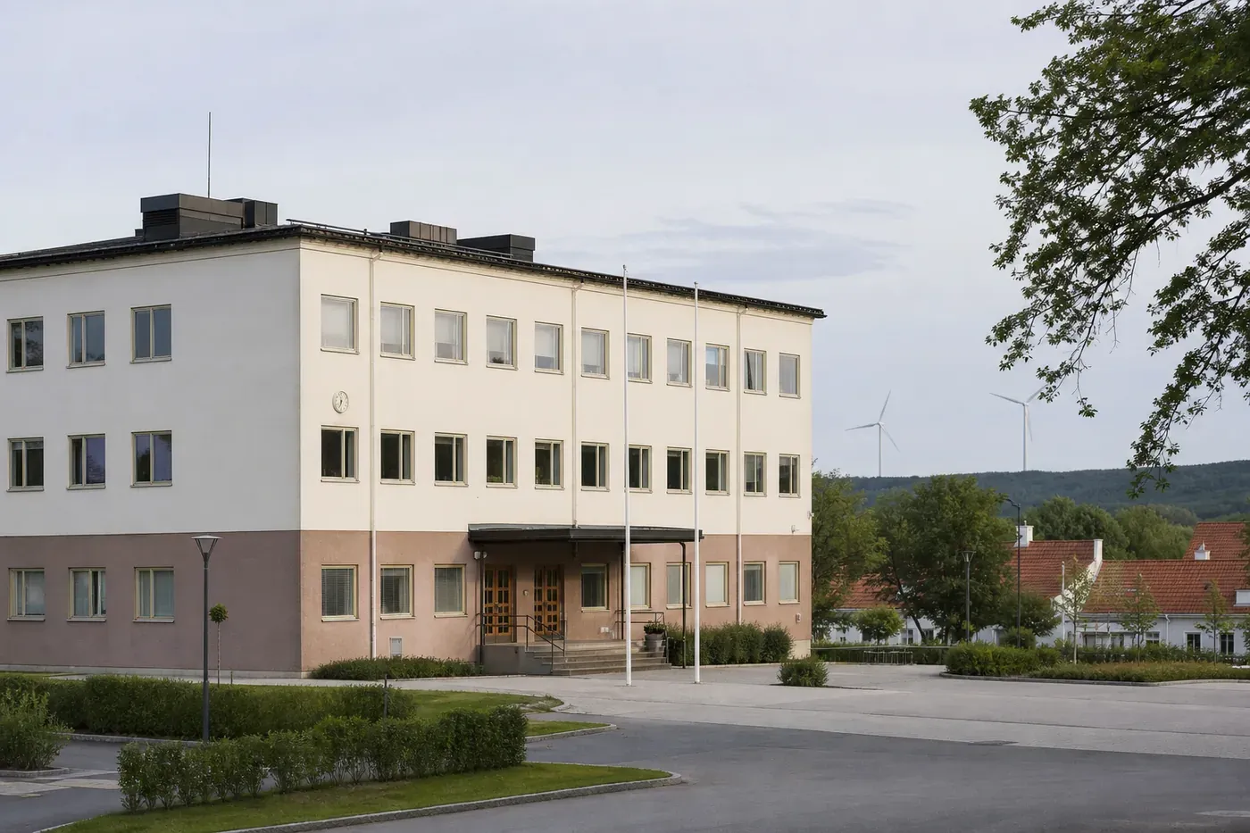 Svenskt kommunhus och vindkraftverk i ett öppet nordiskt landskap