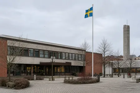 Fasaden på ett svenskt kommunhus med flaggstång en grå dag