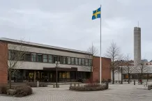 Fasaden på ett svenskt kommunhus med flaggstång en grå dag