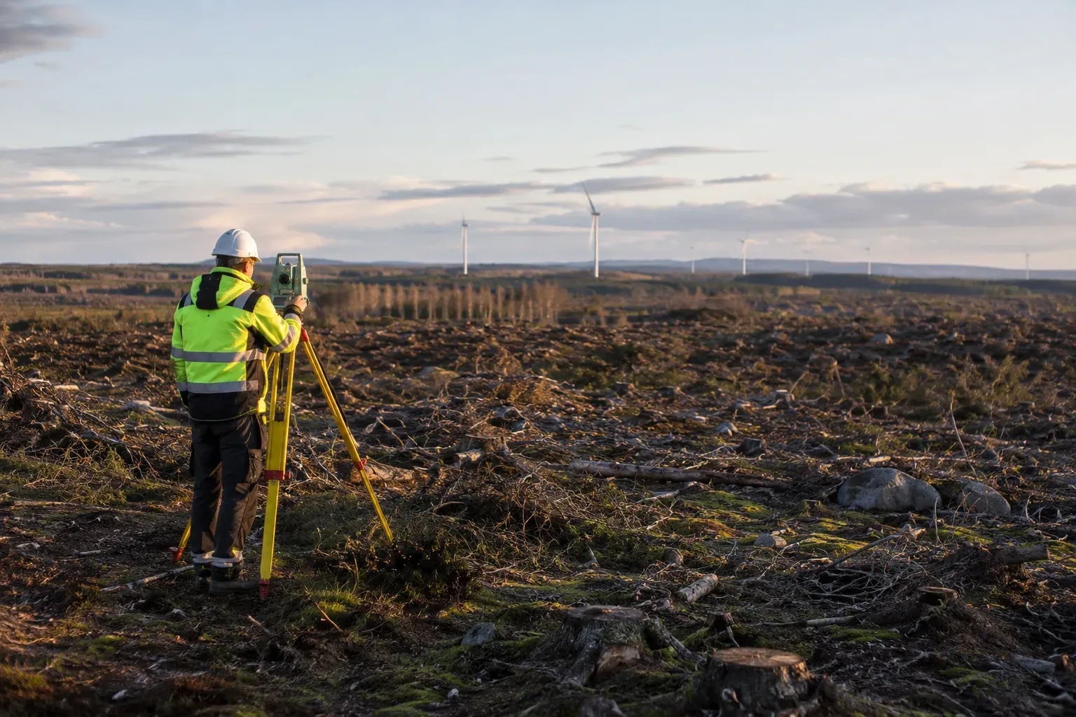 En lantmätare med mätutrustning i ett avverkat skogsområde inför ett vindkraftsprojekt