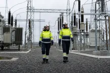 Två nättekniker i skyddskläder i en transformatorstation med ställverk