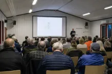 Samrådsmöte i en bygdegård med åhörare framför en projektorduk