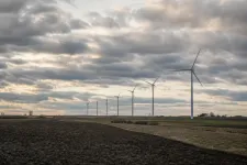 Rad av landbaserade vindkraftverk över ett öppet svenskt slättlandskap