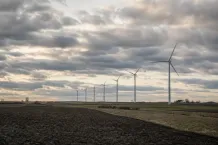 Rad av landbaserade vindkraftverk över ett öppet svenskt slättlandskap